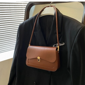Detail of vintage brown saddle bag with gold metal clasp on a black blazer
