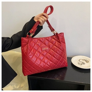 Gros plan du sac cabas matelassé rouge avec coutures en losange et boucles en métal