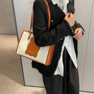 Detail of canvas tote bag featuring orange leather trim and cute bear patch design