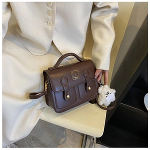 Detail of retro dark brown handbag featuring a gold bear clasp and plush star charm
