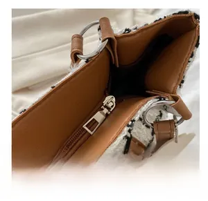 Détail de la fermeture éclair en métal et garniture en cuir sur le sac cabas à carreaux