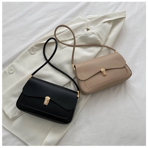 Close-up of minimalist leather saddle bags with golden rectangular locks in black and apricot
