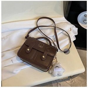 Detail of vintage brown shoulder bag with golden bear motif and plush charm