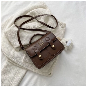 Detail of vintage brown PU leather handbag with bear print and golden buckle accents