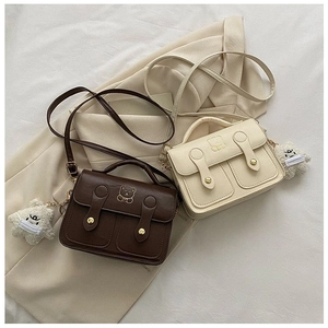 Detail view of small crossbody bags in brown and cream with gold bear hardware