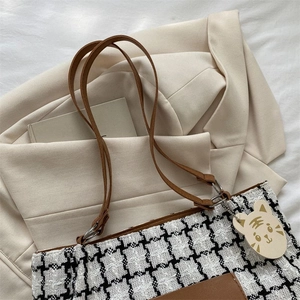 Détail du cabas en tweed à carreaux avec base en cuir marron et pendentif tigre