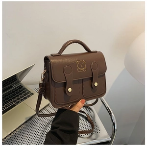 Detail view of a vintage brown crossbody bag featuring a golden bear print and metal buckles