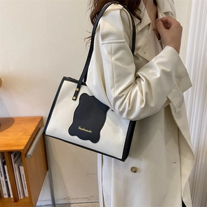 Detail of contrast tote bag with wavy black trim and Guihuashi logo on shoulder