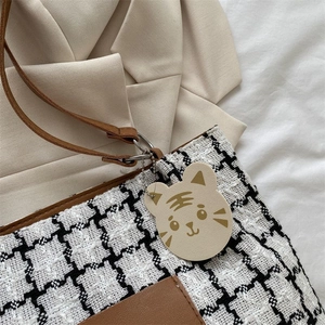 Détail du sac cabas en toile à carreaux avec bordure en cuir et breloque tête de tigre