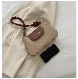 Detail of beige quilted crossbody bag with brown leather strap and phone for size scale