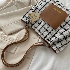 Gros plan sur le sac en tweed pied-de-poule avec poche en cuir brun et logo doré