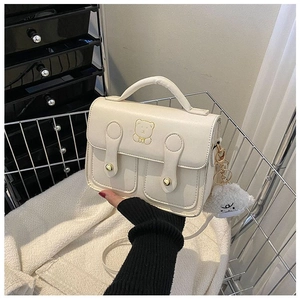 Detail of cream white leather crossbody bag with teddy bear embroidery and plush charm