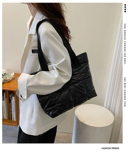 Close-up of black quilted nylon tote bag with rhombus pattern and wide shoulder strap