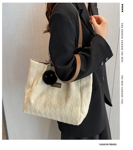 Dettaglio della borsa tote trapuntata beige con tracolla marrone e ciondolo in pelliccia nera