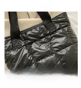 Detail of black quilted puffer tote bag showing soft padded texture and satin finish