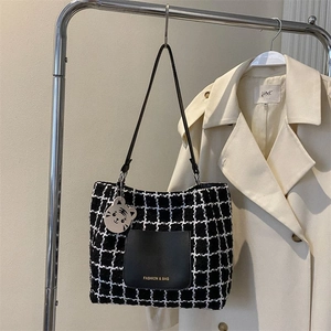 Détail du sac fourre-tout en tweed à carreaux avec poche en cuir et breloque tigre