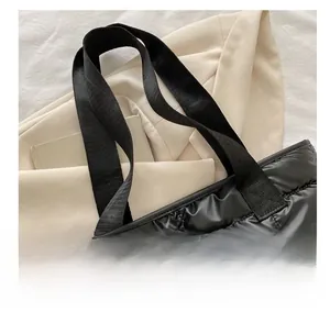 Detail of padded handles and quilted nylon stitching on the black puffer tote bag
