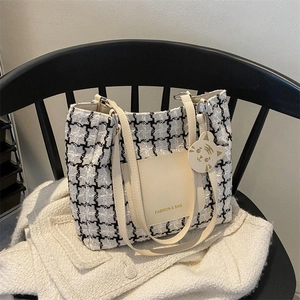 Détail du sac cabas en tweed avec poche en cuir et breloque animale sur chaise
