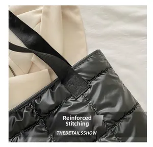 Close-up of reinforced stitching on the shoulder strap of a black quilted tote bag