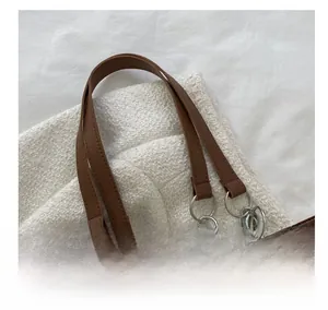 Dettaglio del manico in pelle marrone e degli anelli in metallo argentato della borsa
