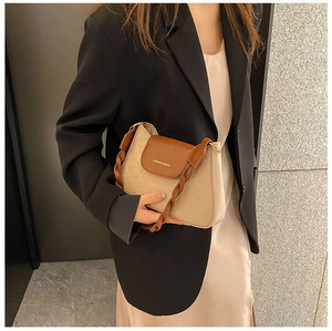 Detail of a beige and brown crossbody bag featuring woven texture strap and embossed logo
