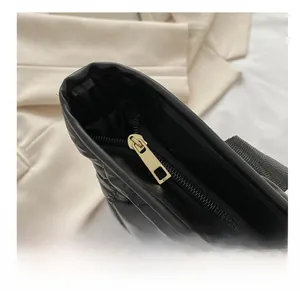 Detailed close-up of a smooth gold metal zipper on a black quilted puffy tote bag