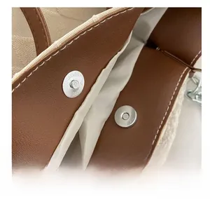 Dettaglio della fibbia magnetica argentata su una borsa tote in peluche con bordo in pelle