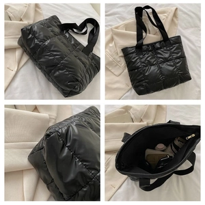 Macro view of black quilted puffer tote bag with glossy finish and large interior space