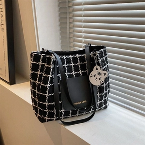 Détail du cabas en toile à carreaux avec poche en cuir et pendentif tigre mignon