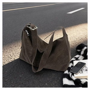 Detail of dark brown matte tote bag with wide strap and silver buckle on asphalt