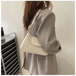 Detail of cream white textured shoulder bag with braided strap on grey blazer