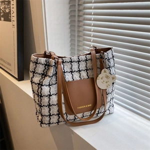 Détail du sac cabas à carreaux noir et blanc avec anses en cuir marron et pendentif tigre