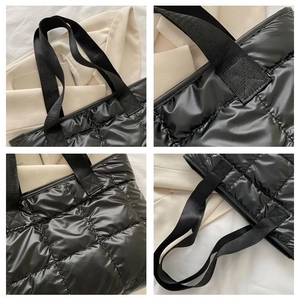 Close-up of quilted black nylon tote bag showing cross-stitch details and padded texture