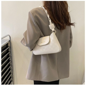 Detail of cream shoulder bag with woven texture and braided strap on model's back