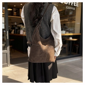 Detail of dark brown suede tote bag with contrast stitching and wide shoulder strap