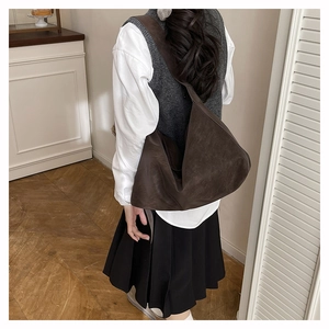 Vista posteriore di una persona con borsa tote in pelle opaca marrone scuro in interni