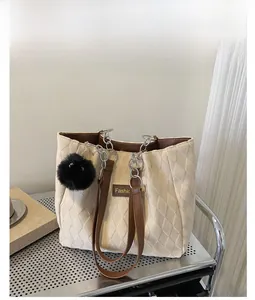 Dettaglio della borsa tote bianca trapuntata con manici marroni e ciondolo a sfera