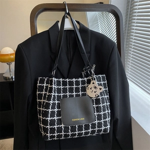 Détail du sac cabas en toile à carreaux avec lanières en cuir noir et pendentif tigre