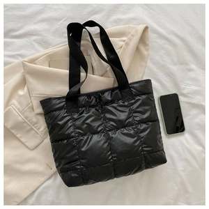 Close-up of black quilted puffer tote bag with diamond texture and wide fabric strap