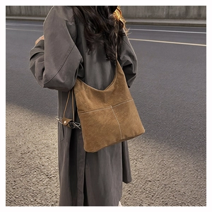Detail of vintage brown suede tote bag with white contrast stitching and relaxed drape