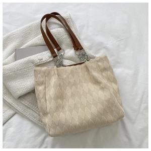 Dettagli macro della borsa trapuntata crema con manici in pelle marrone e maglie in metallo