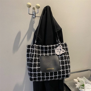 Gros plan du sac cabas en tweed noir et blanc avec poche en cuir et breloque chat