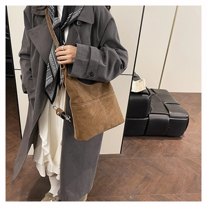 Detail view of large dark brown suede tote bag with contrast stitching worn by model