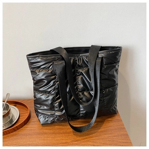 Detail of black quilted puffer tote bag with padded texture and nylon handles