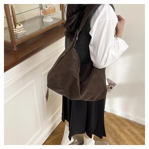 Brown suede shoulder bag shown in a cozy cafe, highlighting its retro minimalist design