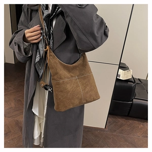 Detail of dark brown suede tote with white contrast stitching and dual exterior pockets