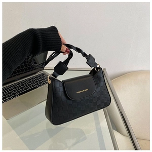 Detail of checkered embossed black bag with woven handle and gold metal hardware