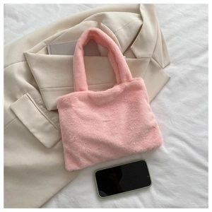 Flat lay of pink plush tote bag with a beige blazer and everyday essentials on white linen