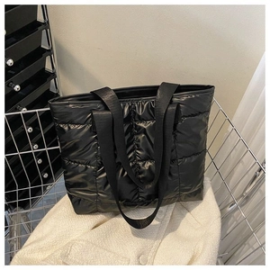 Detail of black quilted down tote bag made of glossy nylon fabric in a metal basket