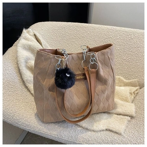 Dettaglio borsa tote trapuntata marrone con etichetta Fashion e ciondolo in peluche nero